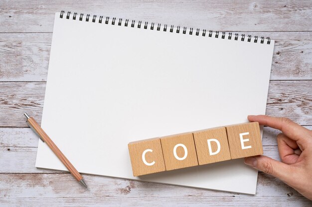 写真 コンセプトのcodeテキスト、ペン、ノート、手が入った木製のブロック。