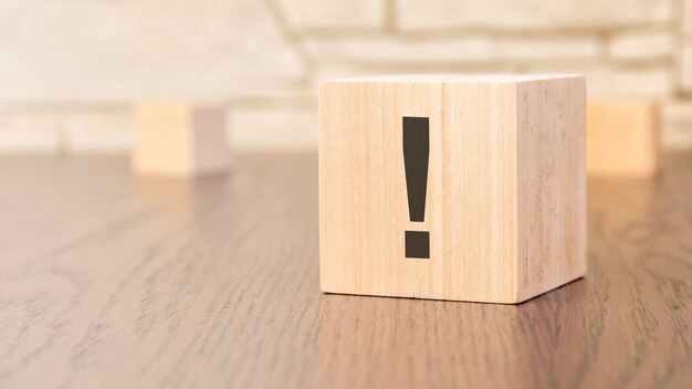 Wooden blocks with exclamation point on wooden table close up space for text