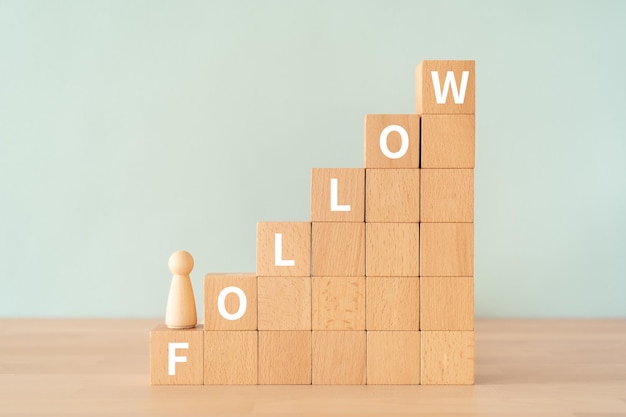 Wooden blocks with FOLLOW text of concept and a human toy.