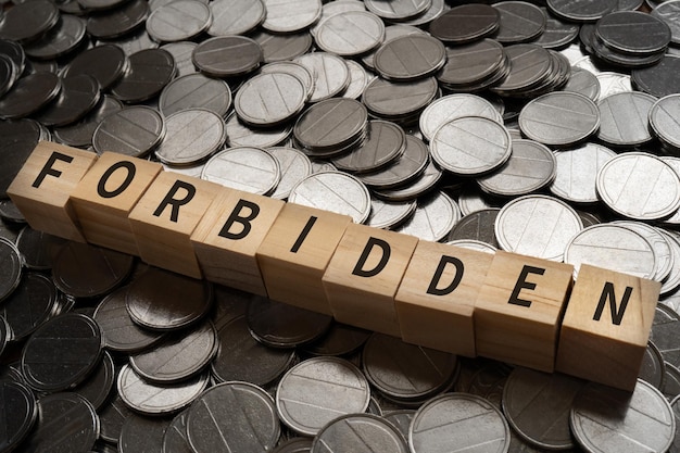 Wooden blocks with FORBIDDEN text of concept and coins.