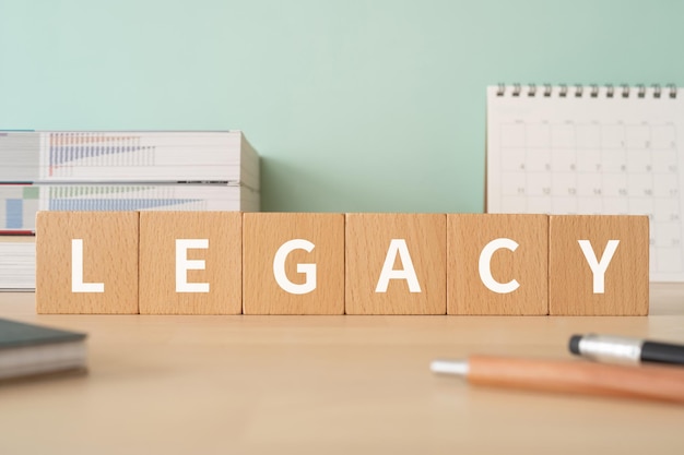 Photo wooden blocks with legacy text of concept, pens, notebooks, and books.