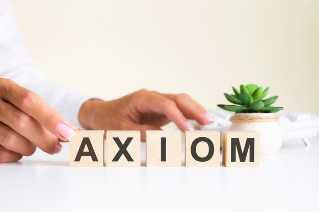 Wooden blocks with letters axiom on the office desk, information and communication background, selective focus on office workplace