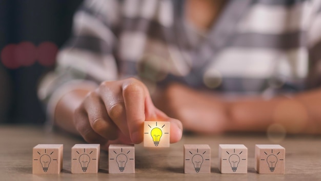 Wooden blocks with light bulbs and yellow color icons and copy space Creative idea solution and innovation concept Idea generation and screening for the product development process