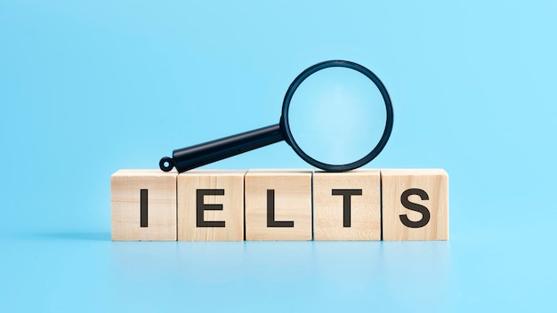 Wooden blocks with a magnifying glass text IELTS International English Language Testing System