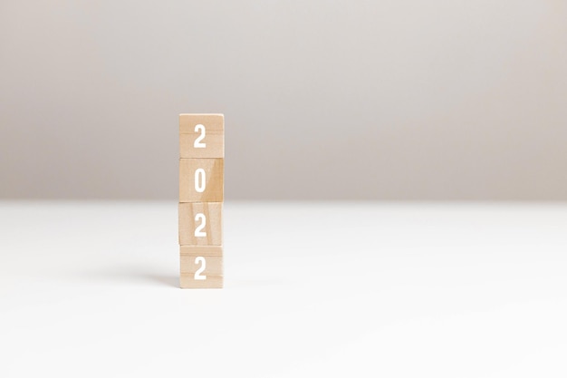 Wooden blocks with message 2022 Number on white table on light background. New Year's composition