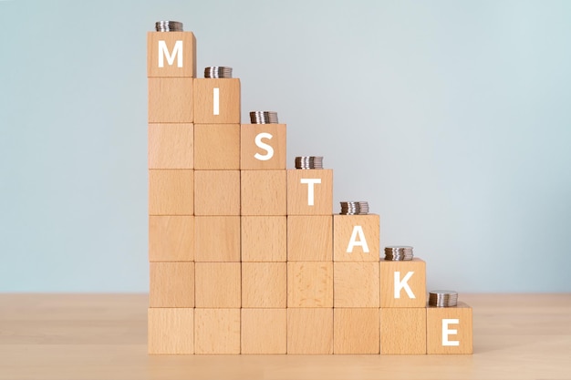 Wooden blocks with MISTAKE text of concept and coins.