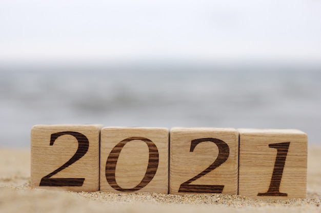 Wooden blocks with the numbers 2021 are located on the sand on the beach