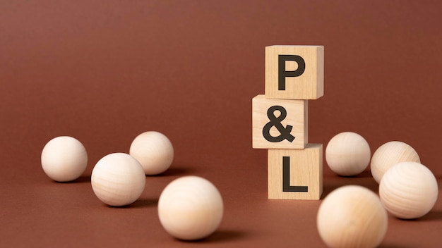 Wooden blocks with text P and L on brown paper business concept pl short for profit and loss