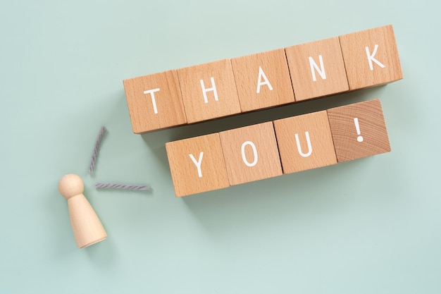 Wooden blocks with THANK YOU text of concept and a human toy.