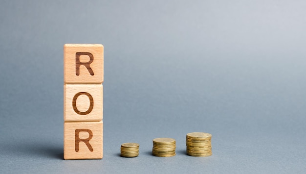 Photo wooden blocks with the word ror and coins high level of business profitability