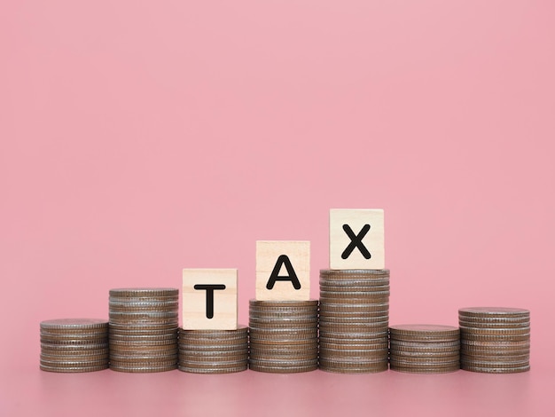 Photo wooden blocks with the word tax and stack of coins the concept about saving money and manage time to paying tax