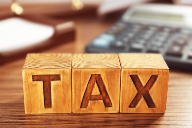 Wooden blocks with word TAX on table closeup