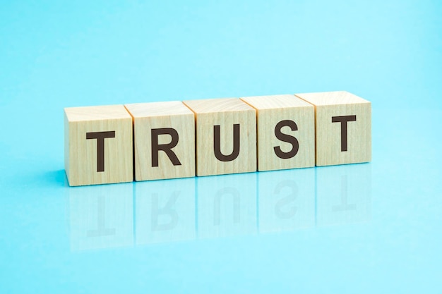 wooden blocks with the word trust blue background
