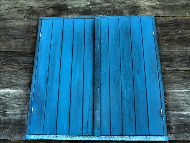 Wooden blue closed shutters on the window of an old traditional Staviany village house Old ethnorural style Wood texture Carpentry craft