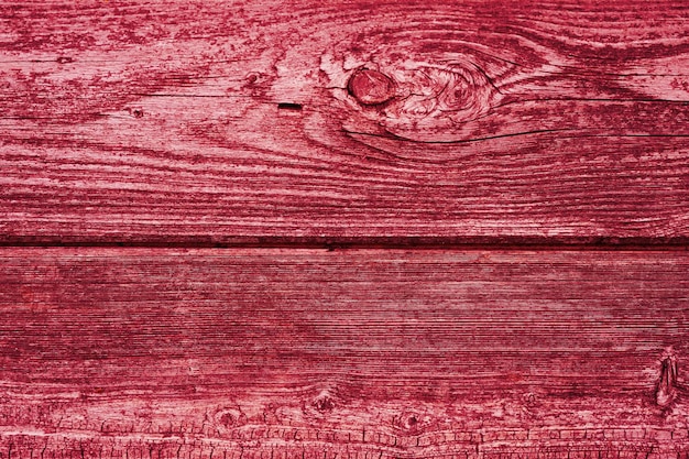 Wooden board background aged weathered red pink purple timber wood planks toned in viva magenta trend color of the year 2023