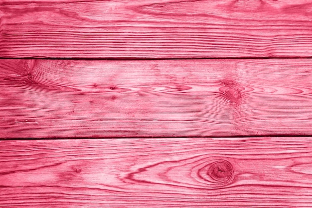 Wooden board background aged weathered red pink purple timber wood planks toned in viva magenta trend color of the year 2023