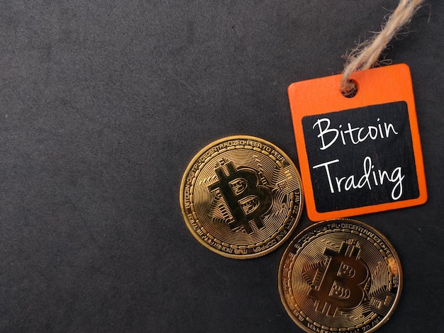 Wooden board and bitcoins with text Bitcoin Trading on a black background