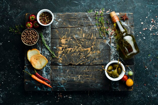 Wooden board on a black stone table with vegetables and spices Food background Top view Rustic style