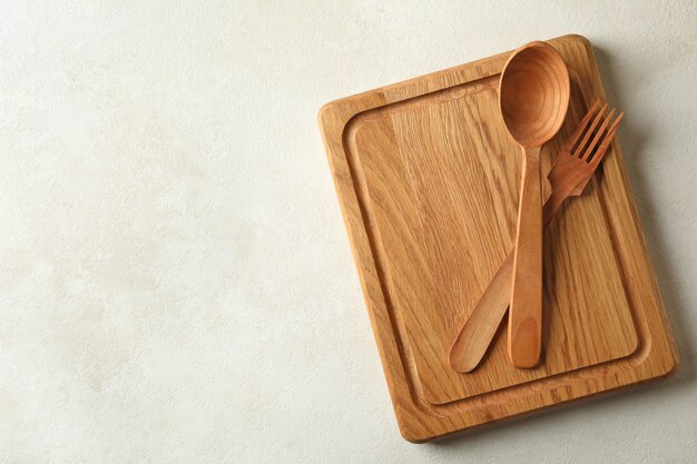 Wooden board and cutlery on white