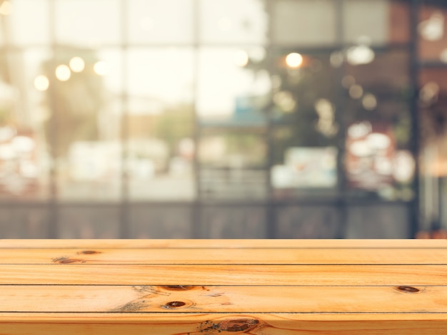 Wooden board empty table in front of blurred coffee shop background.