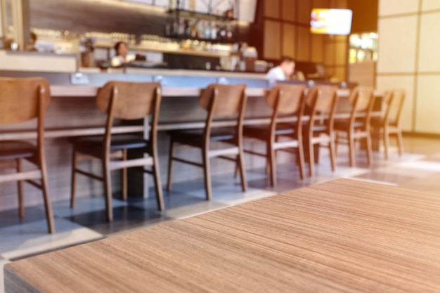 Wooden board empty table top in front of blurred cafe or restaurant