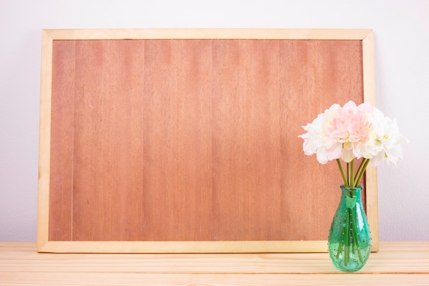 Photo wooden board frame empty copy space and flowers in vase with vintage filter. focus on a vase.