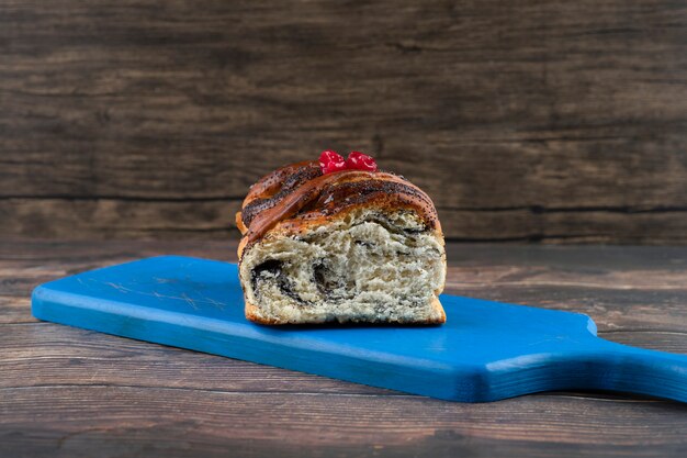 Wooden board of pie with poppy seeds placed on a table .