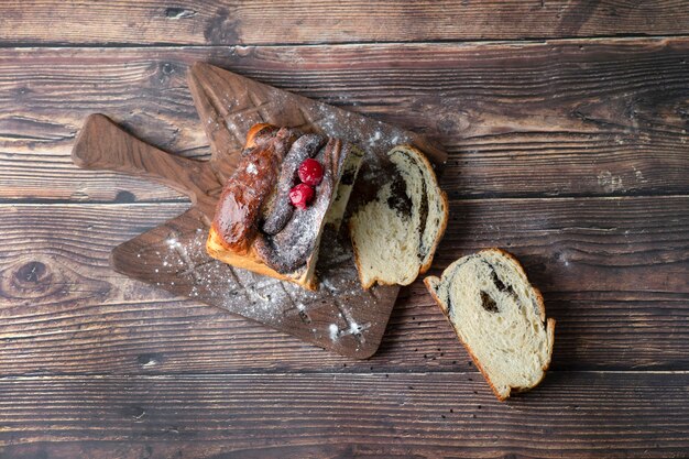 Wooden board of pie with poppy seeds placed on a table .