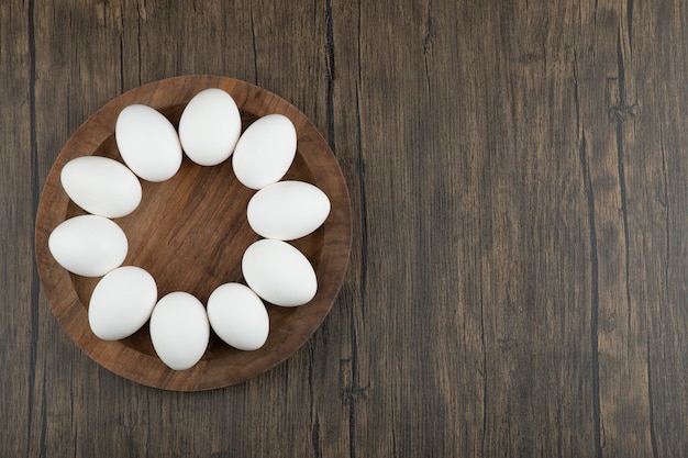 Photo wooden board of raw organic eggs on wooden surface.