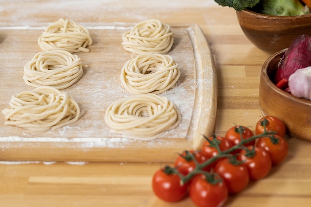 Деревянная доска с вареными спагетти, приготовленными для итальянской пасты