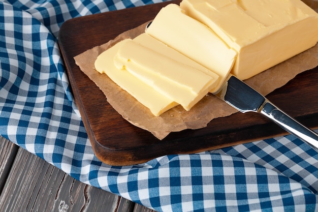 Wooden board with butter on blue checkered napkin