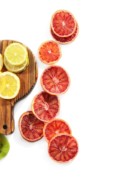 Photo wooden board with citrus slices on white background