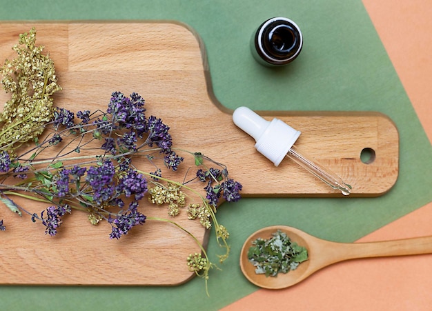 wooden board with dry herbs, pipette and spoon. View from above