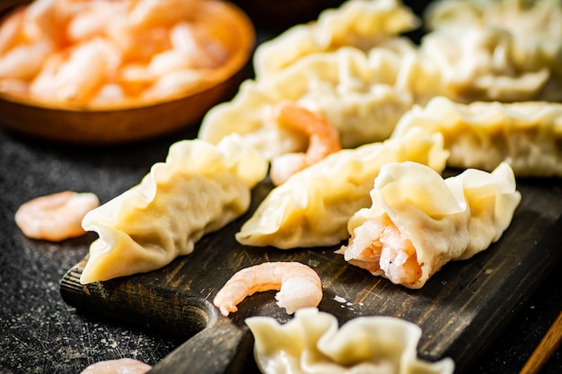 A wooden board with dumplings with shrimps on it.