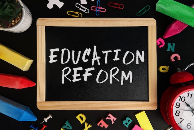 Photo wooden board with education reform text on a background of various colorful subjects