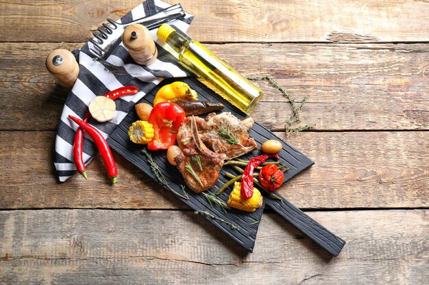 Wooden board with grilled meat on table