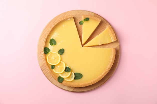 Wooden board with lemon tart on pink, top view