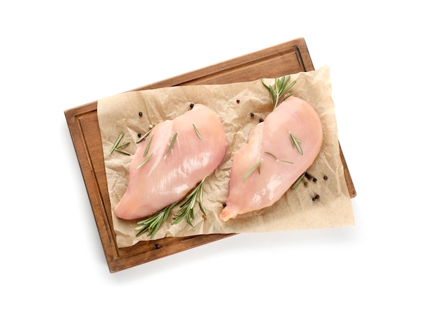 Wooden board with raw chicken fillet on white background