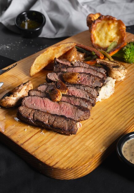 A wooden board with steak and vegetables on it