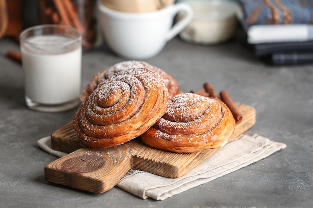 Wooden board with sweet cinnamon rolls on table