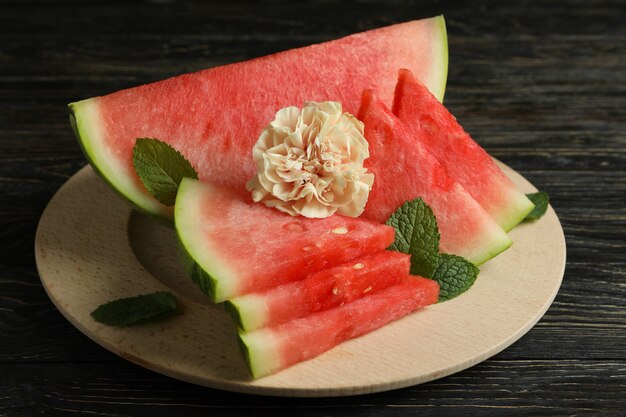 Tavola di legno con fette di cocomero, foglie di menta e fiore