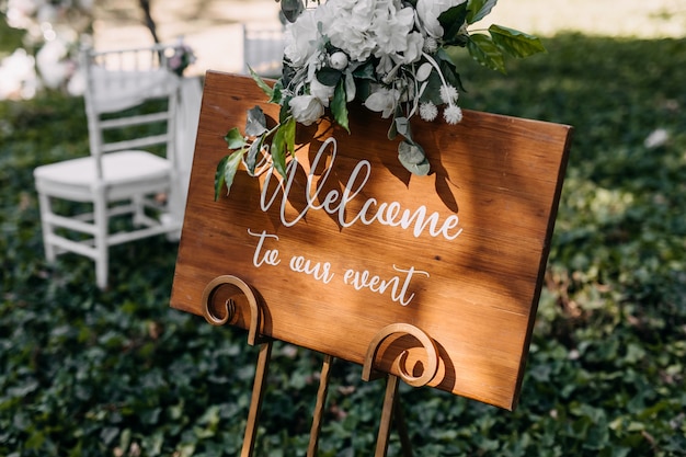 wooden board with welcome to our event text at a wedding ceremony