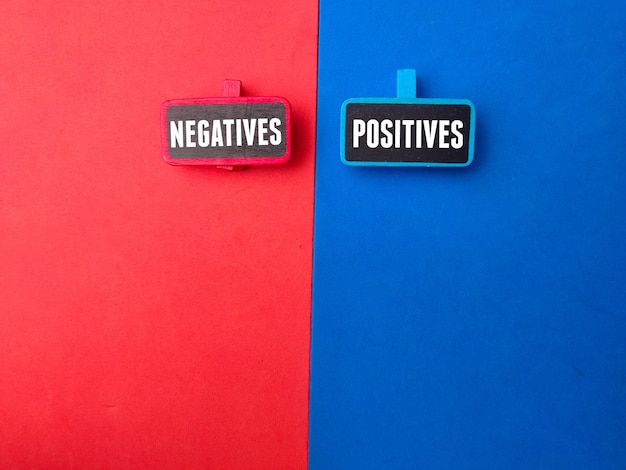 빨간색과 파란색 배경에 NEGATIVES POSITIVES라는 단어가 있는 나무 보드