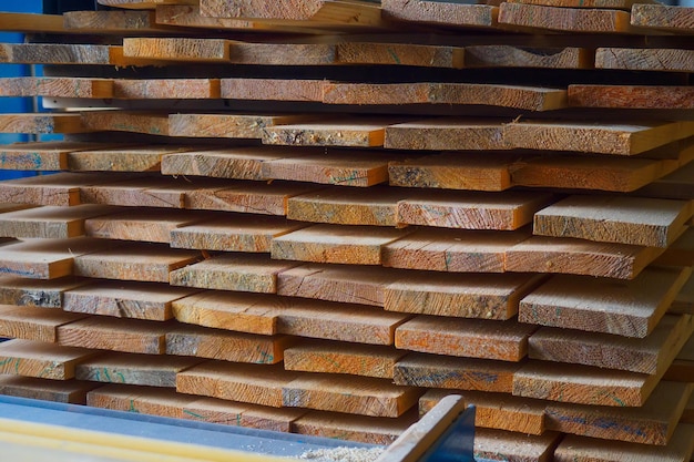 Wooden boards are stacked in a sawmill or carpentry shop Sawing drying and marketing of wood Industrial background