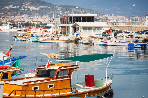 Wooden boards of boats, painted white and brown, moored to the pier.