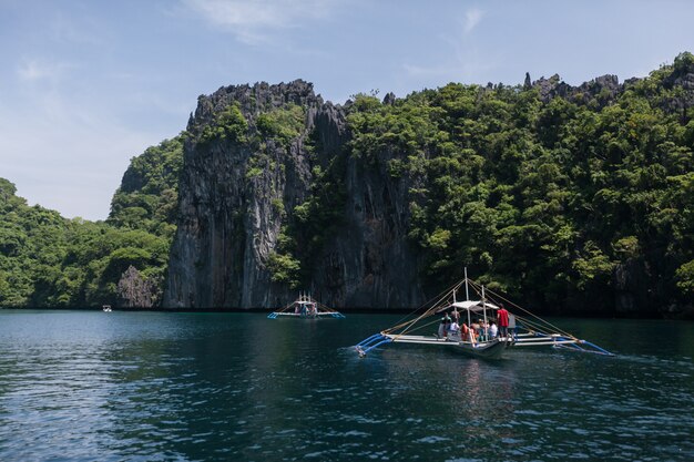 Wooden boat in blue lagoon limestone rocky shore. El Nido, Palawan, Philippines