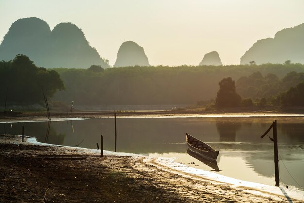 Foto barca di legno sul lago nong thale con montagne calcaree all'alba krabi thailand