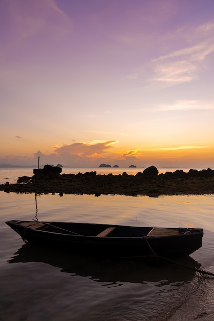 Wooden boat off the coast of a tropical island. Evening, sunset in the ocean. Tropical landscape. Light waves rock the boat