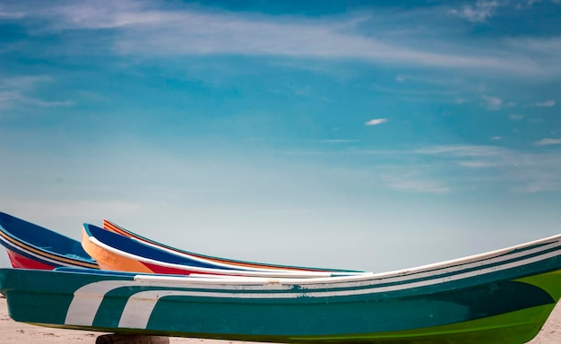 Wooden boats parked on the sand, colorful fishing boats parked near the ocean, closeup of boats stranded on the ocean shore with blue sky and copy space