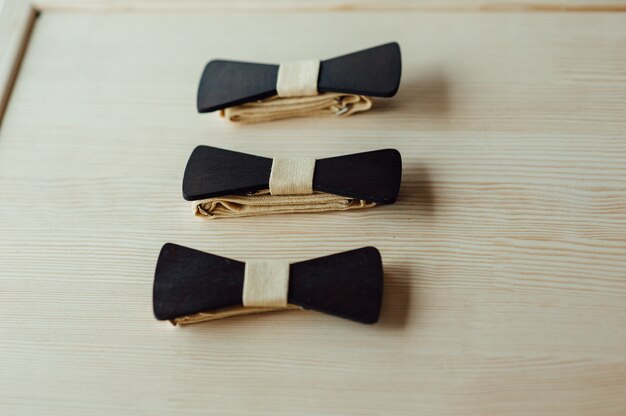 Photo wooden bow ties on a ivory table